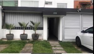 ein weißes Haus mit zwei Palmen davor in der Unterkunft Hotel OrangeTrip in Bogotá