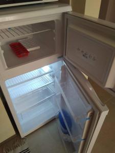 an empty refrigerator with its door open in a kitchen at Nestinarka Complex - Emili Apartment in Tsarevo