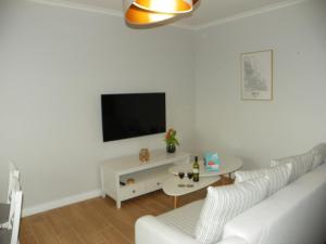 Biały salon z białą kanapą i telewizorem w obiekcie LIRA Apartament w Gdańsku