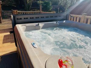 a hot tub on a deck with a drink in it at Owls House, White Cross Bay, Ambleside, Windermere in High Wray