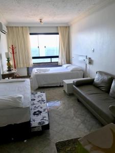 a hotel room with two beds and a couch at Flat Vista Mar Frente ou Lateral na Barra em Salvador in Salvador