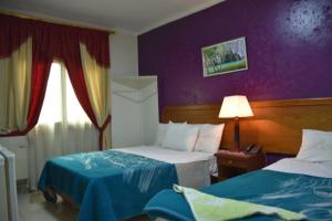 een hotelkamer met 2 bedden en een paarse muur bij Sun Hostel Cairo in Caïro