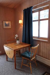 Zimmer mit einem Holztisch, einem Stuhl und einem Fenster in der Unterkunft Fredheimbrygga in Andenes