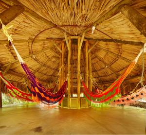 a large wooden room with hammocks hanging in it at Hotel Waya Guajira in Albania