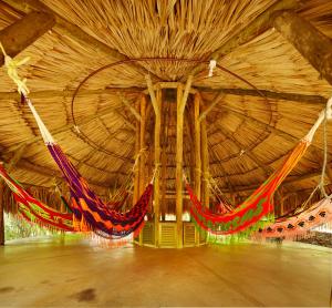 Habitación grande de madera con hamacas colgadas. en Hotel Waya Guajira, en Albania