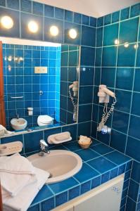 a blue tiled bathroom with a sink and a mirror at Hotel Il Piccolo Golf in Porto Cervo