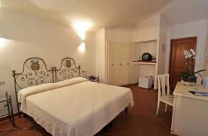 a bedroom with a white bed and a table and chair at Hotel Il Piccolo Golf in Porto Cervo