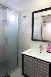 a bathroom with a sink and a shower with a mirror at Casa Da Praia "AL" in Monte Gordo