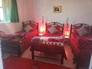 Habitación con 3 camas, sábanas rojas y luces. en Dar El Idrissi, en Rabat