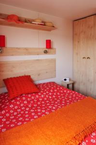 a bedroom with a red bed with an orange blanket at La Drugère - Gîtes et Roulottes in Nyons