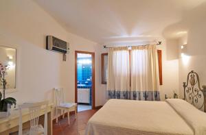 a bedroom with a bed and a desk and a window at Hotel Il Piccolo Golf in Porto Cervo