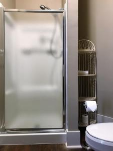 La salle de bains est pourvue d'une douche en verre et de toilettes. dans l'établissement Hardeman House Bed and Breakfast, à Nacogdoches