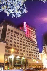 徐州市にあるジンユアン ジンリン プラザ 徐州のネオンサインが上のホテルの建物