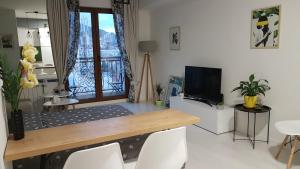 uma sala de estar com uma mesa com cadeiras e uma televisão em BS Apartment Flatiron em Skopje