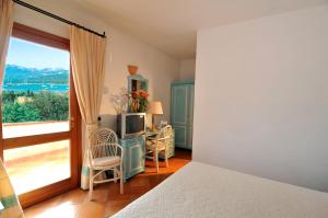 a bedroom with a bed and a tv and a balcony at Hotel Il Piccolo Golf in Porto Cervo