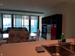 a kitchen with a sink and a living room at ReadySet Apartments at Southbank One in Melbourne