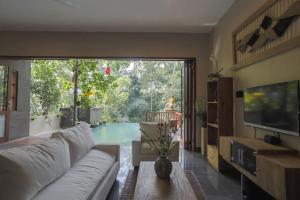 sala de estar con sofá, TV y piscina en Harum Sari Ubud Private Villa, en Ubud