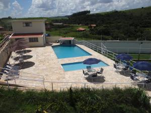 a swimming pool with two umbrellas and chairs at Pousada Canto dos Canários in Socorro