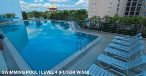 - une grande piscine avec des chaises longues à côté d'un bâtiment dans l'établissement Astana Wing - Riverside Majestic Hotel, à Kuching
