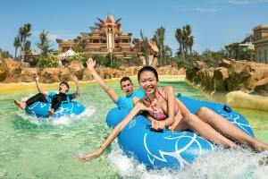 a man and a woman sitting on a surfboard in a pool at Atlantis Sanya in Sanya