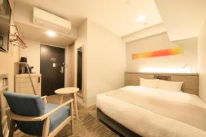 1 dormitorio con 1 cama, 1 silla y 1 mesa en S-peria Inn Osaka Hommachi, en Osaka