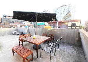 a wooden table and chairs with an umbrella on a rooftop at GangnamStay - Foreign Female Only in Seoul