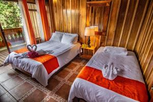 a bedroom with two beds and a window at Cabañas Hoja Verde in Monteverde Costa Rica