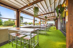 a row of tables and chairs in a room with windows at Narrabeen Sands Hotel by Nightcap Plus in Narrabeen