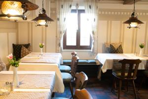 ein Restaurant mit Tischen und Stühlen und einem Fenster in der Unterkunft Hotel-Gasthof Weisses Ross in Schwaig bei Nürnberg
