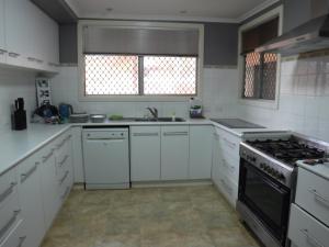 uma cozinha com armários brancos e um forno com placa de fogão em Meekatharra Outback Beach House em Meekatharra