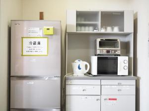 大阪市にある新大阪ユースホステルの冷蔵庫と電子レンジ付きのキッチン