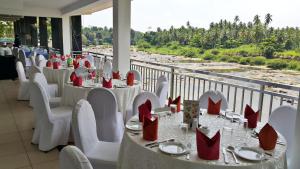 a restaurant with white tables and red chairs and a balcony at Hotel Elephant Park "Grand Royal Pinnalanda" in Pinnawala