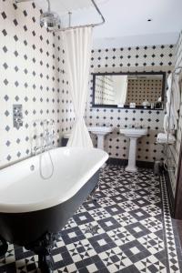 a bathroom with a white tub and a black and white tiles at Boundary Shoreditch in London