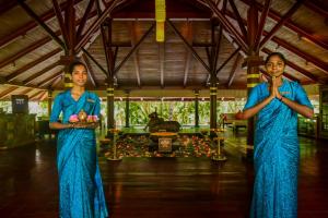 two women in blue robes standing in a room with their hands praying at Niraamaya Wellness Retreats, Surya Samudra, Kovalam in Kovalam