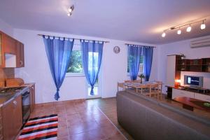 a living room with a couch and a kitchen with blue curtains at APARTMAN KATY in Šilo