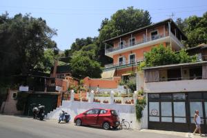 un'auto rossa parcheggiata di fronte a un edificio di Panorama a Perama