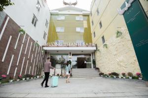 Muong Thanh Sapa Hotel في سابا: رجل وامرأة يسيران أمام مبنى