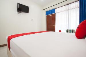 a bedroom with a white bed with a red pillow at RedDoorz @ Panglima Sudirman Probolinggo in Probolinggo