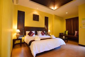 um quarto com uma grande cama branca e um banco em Chalicha Resort em Chumphon