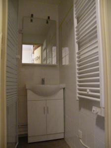 ein weißes Badezimmer mit einem Waschbecken und einem Spiegel in der Unterkunft Au Coeur De La Station in Les Deux Alpes