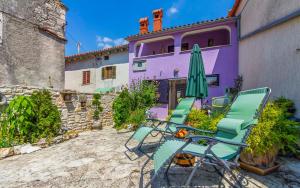 a group of chairs and an umbrella in front of a purple house at House Rakalj 561 in Rakalj