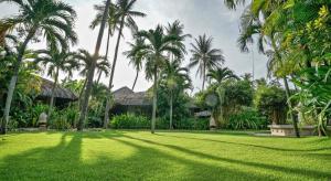 a lawn with palm trees in front of a house at Sailing Club Resort Mui Ne in Mui Ne