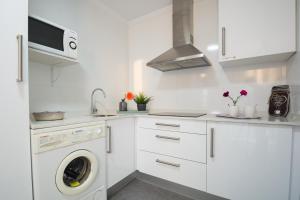 a white kitchen with a washing machine and a sink at Apartamento El Pedregal Playa de Ris in Noja