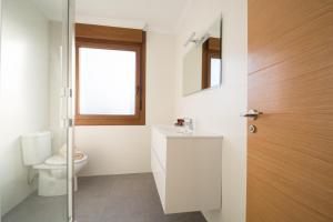a bathroom with a toilet and a sink and a window at Apartamento El Pedregal Playa de Ris in Noja +25 photos