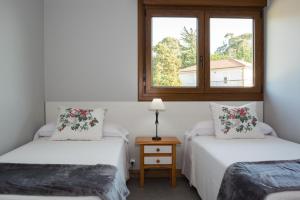 two twin beds in a room with a window at Apartamento El Pedregal Playa de Ris in Noja