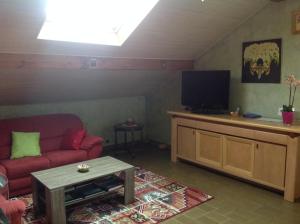 sala de estar con sofá rojo y TV de pantalla plana en La Sapotine, en Étrembières