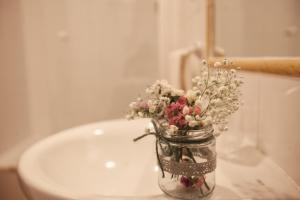 um frasco de pedreiro cheio de flores em cima de um lavatório em Hotel El Repelao em Covadonga