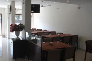 comedor con mesas y sillas y TV en Hotel Ambica, en Daman