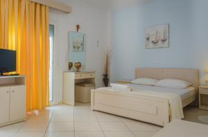 スカラ・ポタミアスにあるErics Apartmentのベッドルーム(ベッド1台、テレビ、オレンジ色のカーテン付)