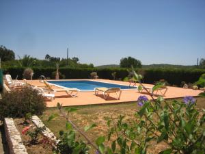 a swimming pool in a yard with lounge chairs at Quinta das AVES - Apartamento T2 com Piscina Comum in Odiáxere